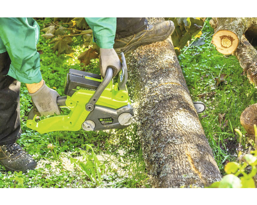 Une personne scie un tronc d''arbre avec une tronçonneuse à batterie.