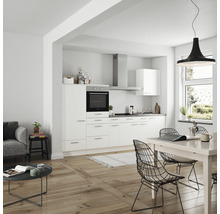 Helles Wohnzimmer mit Einbauküche, Esstisch und Sofa.