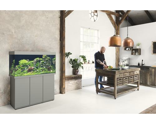 Pièce lumineuse avec aquarium sur un meuble et personne en train de cuisiner