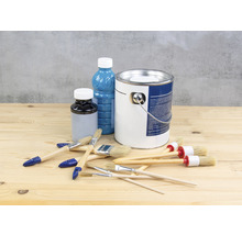 Seau de peinture, flacon de vernis et pinceaux sur une table en bois