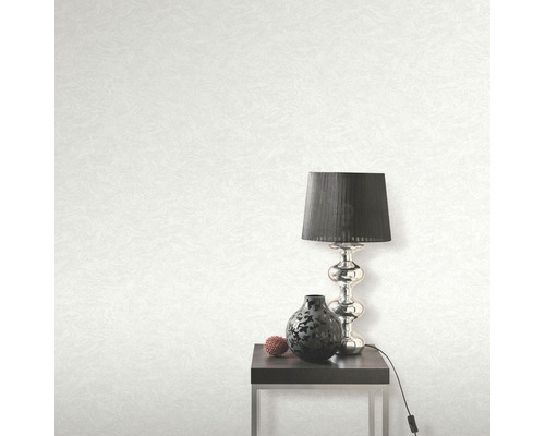 Papier peint clair avec texture, lampe de table, décoration et table d''appoint dans la pièce.