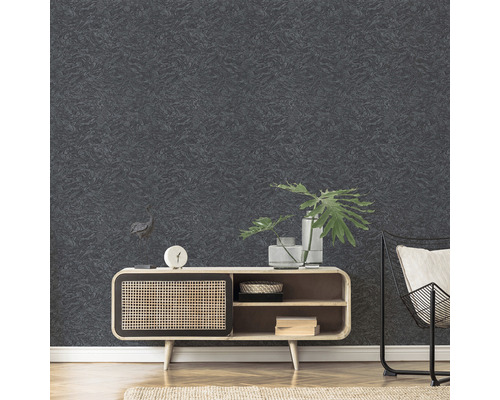 Nahaufnahme einer strukturierten, dunklen Tapete im Wohnzimmer, kombiniert mit einem Holzschrank und einem Metallstuhl.