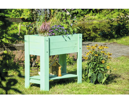Jardinière sur pieds en bois avec plantes et hôtel à insectes dans le jardin