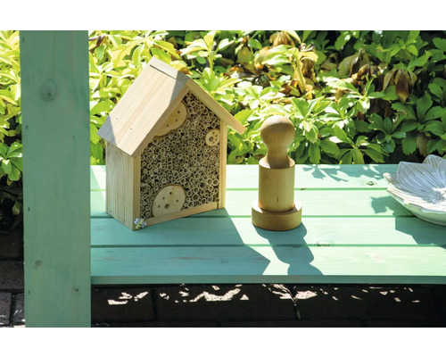 Hôtel à insectes en bois avec matériau de remplissage en tubes et décorations en bois.