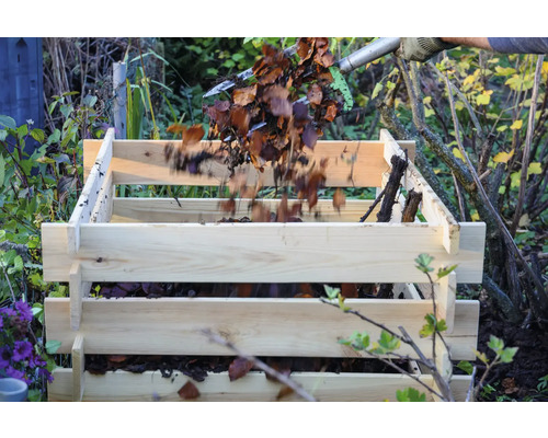 Remplissage d''un composteur en bois avec des feuilles et des déchets de jardin.