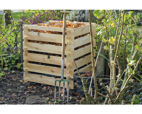 Composteur en bois avec des feuilles et une fourche à fumier