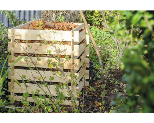 Composteur en lattes de bois rempli de feuilles dans le jardin