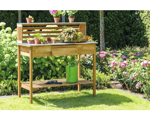 Table de jardin en bois avec tiroir, étagère et pots de fleurs dans le jardin