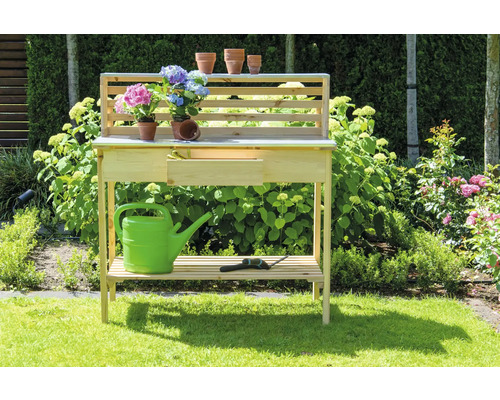 Table de jardin en bois avec étagère, tiroir, arrosoir, fleurs et outil de jardin dans le jardin
