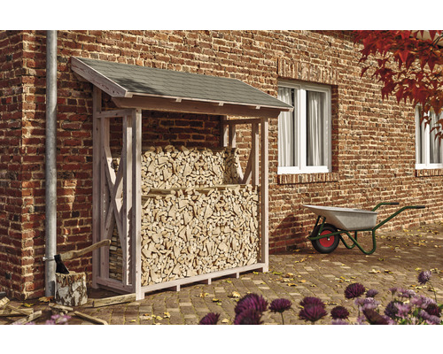 Kaminholzunterstand SKAN HOLZ Paul 1 190 x 70 x 229 cm natur Holzlager gefüllt mit Brennholz im Außenbereich neben einer Schubkarre.