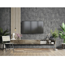 Wohnzimmer mit Fernseher, Lowboard, Stuhl und Dekorationen vor einer Wand mit Struktur