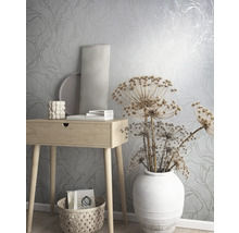 Szene mit floral gemusterter Tapete, Holztisch, Dekoration und Korb