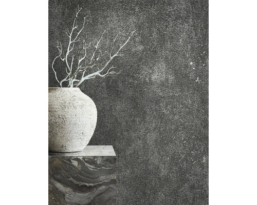 Nahaufnahme einer Vase mit Ästen vor einer dunklen, strukturierten Wand