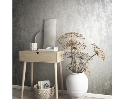 Intérieur décoratif avec console, vase et fleurs séchées devant un papier peint structuré.