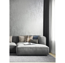 Graues Sofa mit Kissen auf einem Teppich vor einer strukturierten Wand