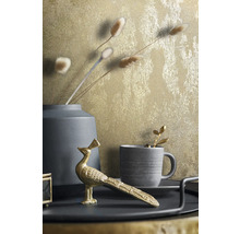Scène décorative avec vase, tasse et figurine de paon sur un plateau devant un mur à motifs