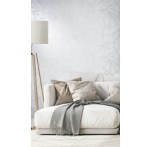 Wohnzimmer mit Couch, Kissen, Decke, Stehlampe und Tapete mit Pflanzenmuster