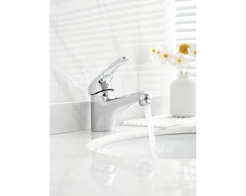 Glänzender Wasserhahn aus Metall auf einem weißen Waschbecken