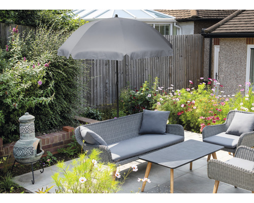 Scène de jardin avec parasol gris, salon de jardin en rotin et four en argile sur une terrasse