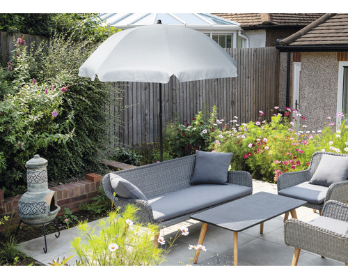 Ensemble de meubles de jardin avec parasol, canapé, fauteuils et table sur une terrasse.