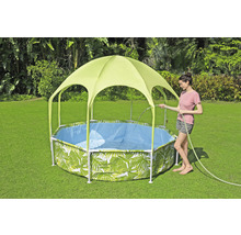 Gartenszene mit einem Framepool mit Blättermuster und Sonnenschutzdach, während eine Frau den Pool mit einem Gartenschlauch befüllt.