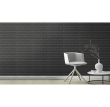 Raumansicht mit schwarzen Fliesen an der Wand, einem Stuhl und einem Tisch