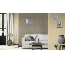 Salon avec papier peint à motifs, canapé, lampadaire et éléments décoratifs pour une ambiance chaleureuse.