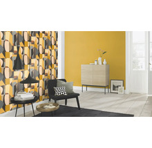 Wohnzimmer mit gemusterter Tapete, Kommode und Sessel.