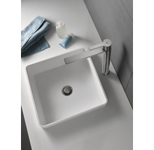 Sur un lavabo se trouvent un lavabo à poser avec robinet, une serviette et des articles de toilette