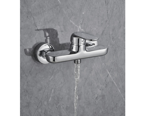 Duscharmatur mit Wasserstrahl vor grauer Wand