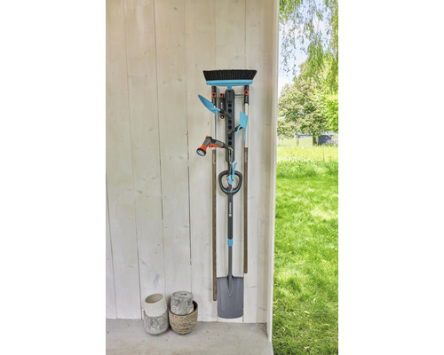 Support d''outils de jardin fixé à un mur avec des outils de jardin tels qu''une bêche, un balai et un tuyau d''arrosage