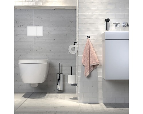 Salle de bains moderne avec WC suspendu, plaque de commande, brosse de toilette, porte-papier, serviette et lavabo