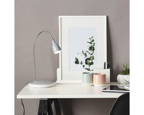 Scène de table avec lampe de bureau, cadre photo et décoration sur un bureau.