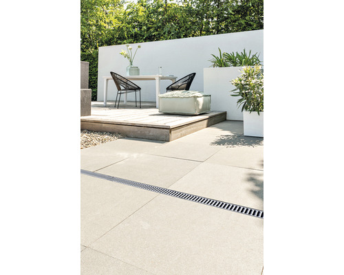 Aménagement de terrasse avec caniveau de drainage, table, chaises, plantes et pouf