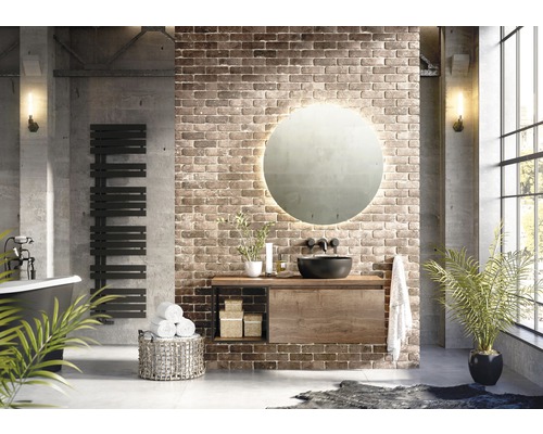 Badezimmer mit Waschtisch, Spiegel, Handtuchwärmer und Dekoration vor Ziegelwand