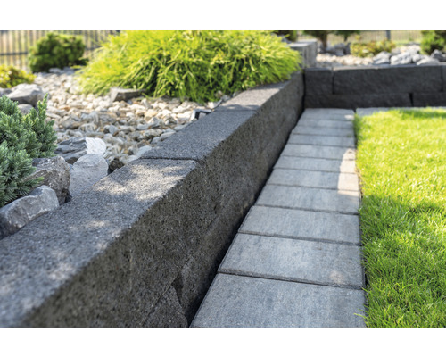 Vue du jardin avec pelouse, pierres de mur et dalles de trottoir