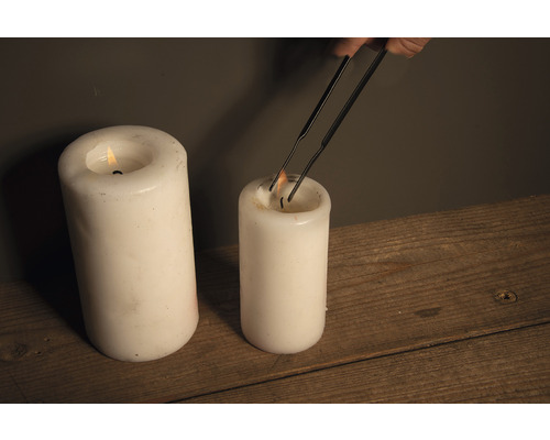 Kerze wird mit einer Dochtschere gekürzt