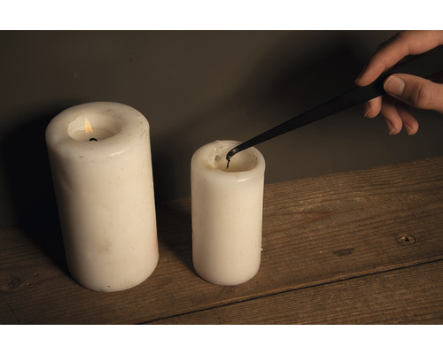 Kerzenlöscher im Einsatz zum Löschen einer Stumpenkerze neben einer brennenden Kerze