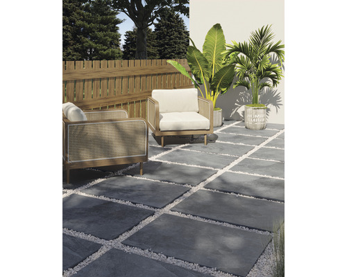 Aménagement de terrasse avec dalles en pierre grises, graviers décoratifs blancs, deux fauteuils, une clôture en bois et des plantes