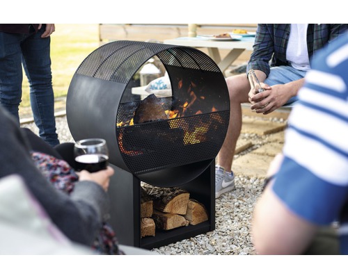 Foyer circulaire en métal avec rangement pour bûches dans le jardin avec des personnes