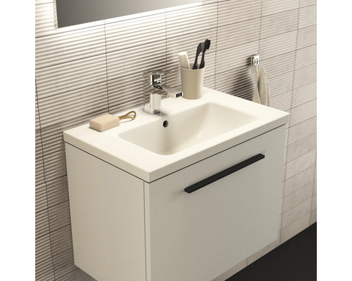 Waschtisch mit Unterschrank, Armatur, Seife, Handtuch und Zahnbürsten in einem Badezimmer.