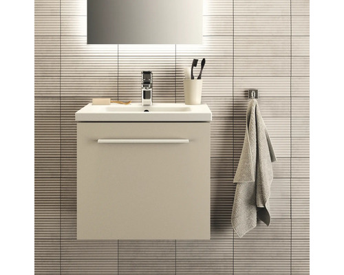 Badezimmer-Szene mit Waschtischunterschrank, Waschbecken, Armatur, Spiegel, Handtuch und Badaccessoires vor einer gefliesten Wand