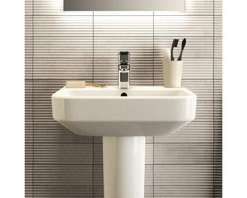 Waschbecken mit Armatur, Seife, Zahnbürsten und Fliesen im Badezimmer