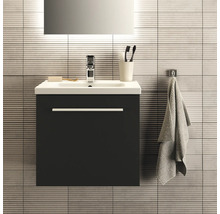 Meuble-lavabo avec meuble bas, robinetterie, serviette et accessoires de salle de bains devant un mur carrelé