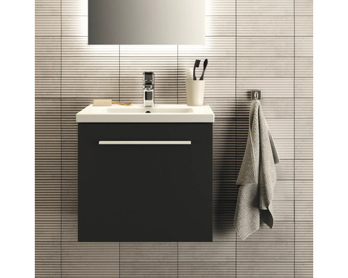 Waschtisch mit Unterschrank, Armatur, Handtuch und Badaccessoires vor gefliester Wand