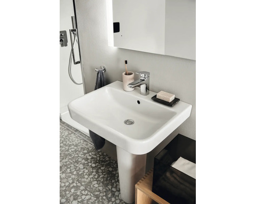 Waschtisch mit Armatur und Badaccessoires in einem Badezimmer.