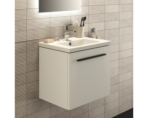 Waschbeckenunterschrank mit Armatur und Badaccessoires vor einer strukturierten Wand