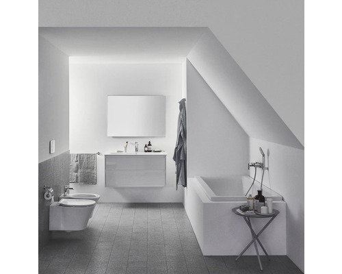 Helles Badezimmer mit Waschtisch, Spiegel, Badewanne und Bidet in einem Dachgeschoss.