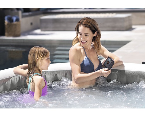 Femme et enfant se détendent dans un jacuzzi extérieur avec commande numérique