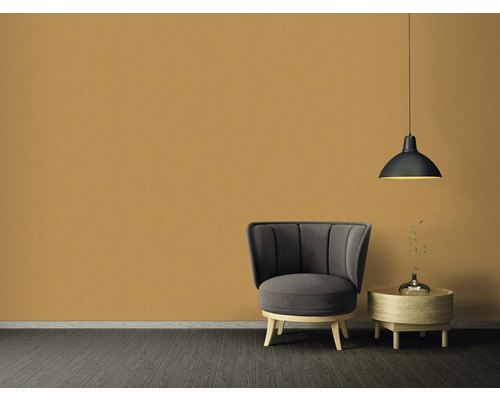 Wohnzimmer mit Sessel, Beistelltisch und Hängelampe vor einer einfarbigen Wand